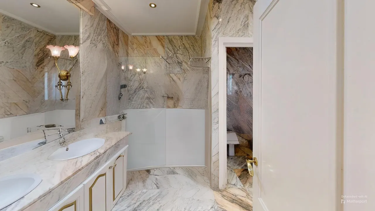 Baño en suite del dormitorio principal con revestimiento de mármol