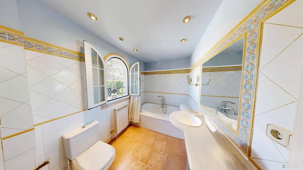 Baño en suite con bañera y ventana en arco