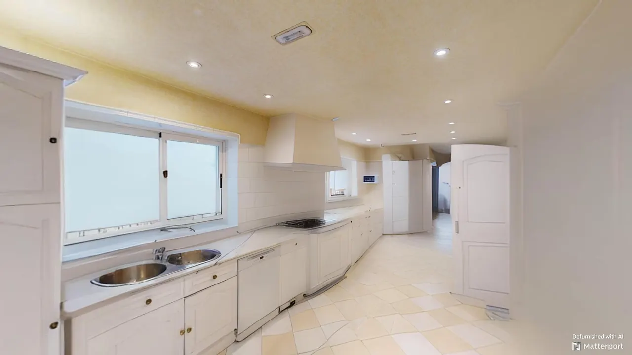 Cocina con mobiliario blanco y doble fregadero bajo la ventana