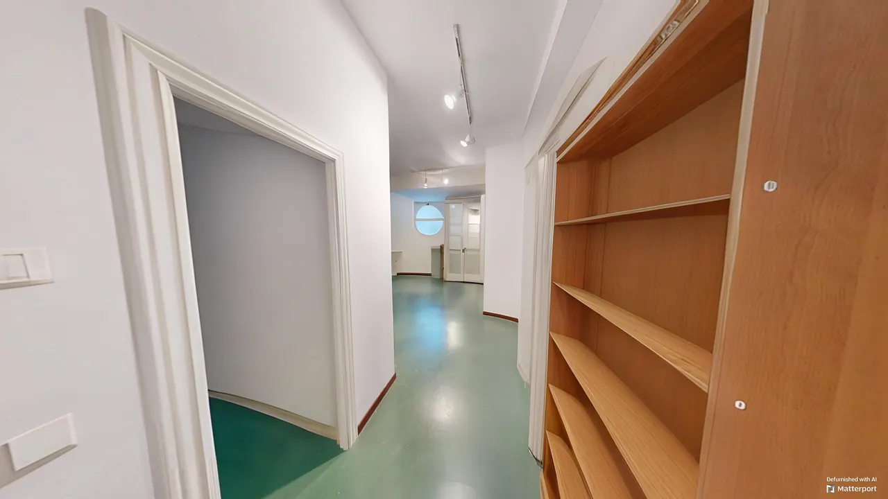 Sala del semisótano usada como gimnasio, con estanterías de madera